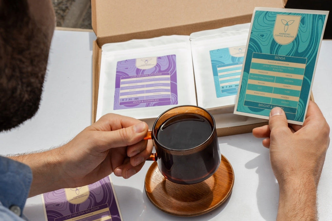 Man holding subscription coffee card while drinking a cup of coffee, sat in the sun.