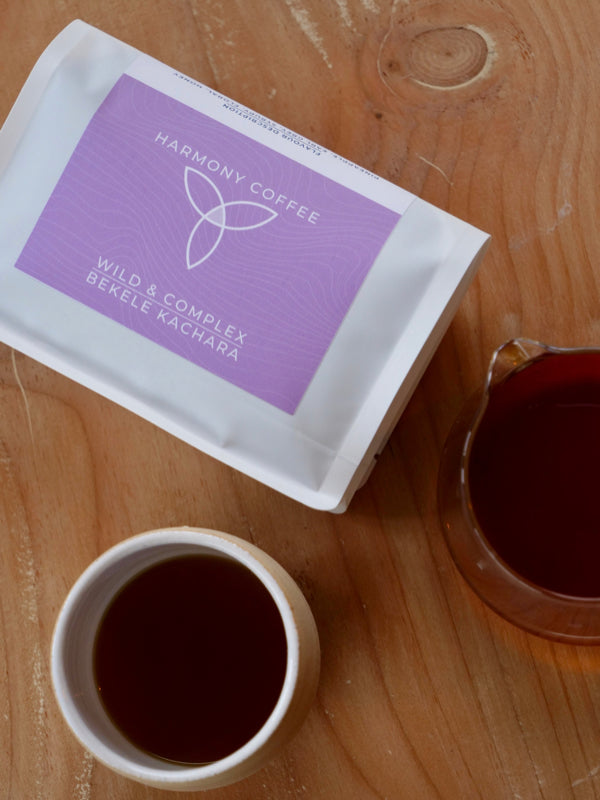 BEKELE KACHARA, roasted by Harmony Coffee (York) on a wooden surface with a cup of coffee.