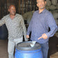 Bekele Yutute standing next to a blue barrel inside a rustic building with wooden walls.
