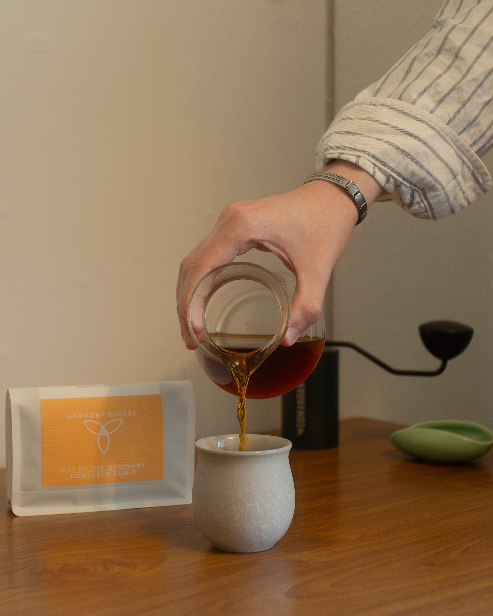 Consuelo Rubio Anaerobic sidra coffee poured into a cup on a table from a glass carafe, with a commandant c40 in the background
