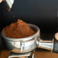Coffee grounds being ground fresh into a portafilter basket.