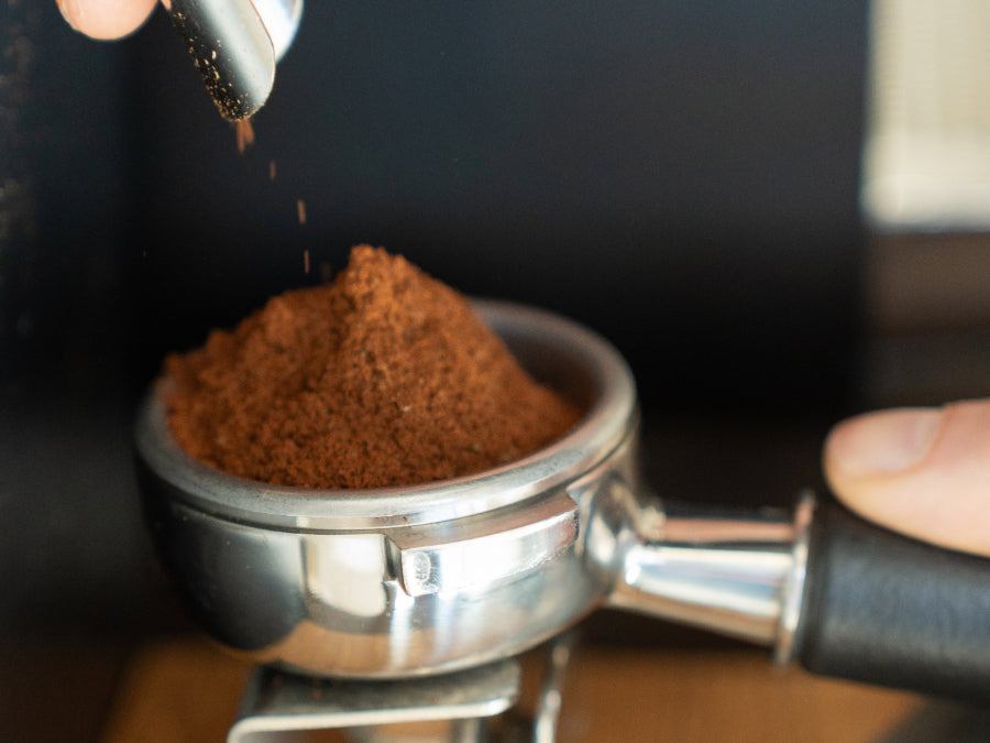 Coffee grounds being ground fresh into a portafilter basket.