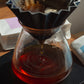 Coffee being brewed in a glass carafe with a paper filter.