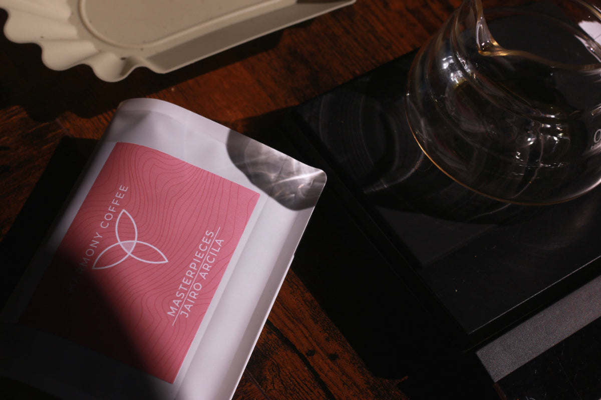 Harmony Coffee Jairo Arcila Java coffee package with a glass carafe on a wooden surface