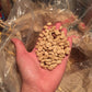 Hand holding a handful of roasted Coffee Parchment with a jute bag in the background.