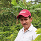 Man wearing a red cap with 'Cofinet' branding in a coffee plantation.