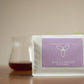 A stand-up coffee bag labeled 'Harmony Coffee' and 'Wild & Complex Mutambu' sits on a wooden surface with a blurred glass of coffee in the background against a warm beige wall.
