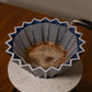 Blue and white coffee filter with coffee grounds on a wooden surface