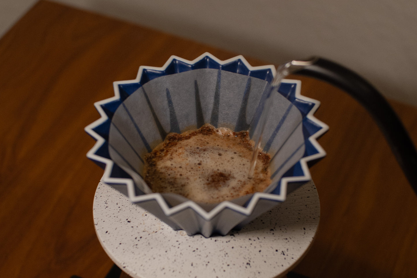 Blue and white coffee filter with coffee grounds on a wooden surface