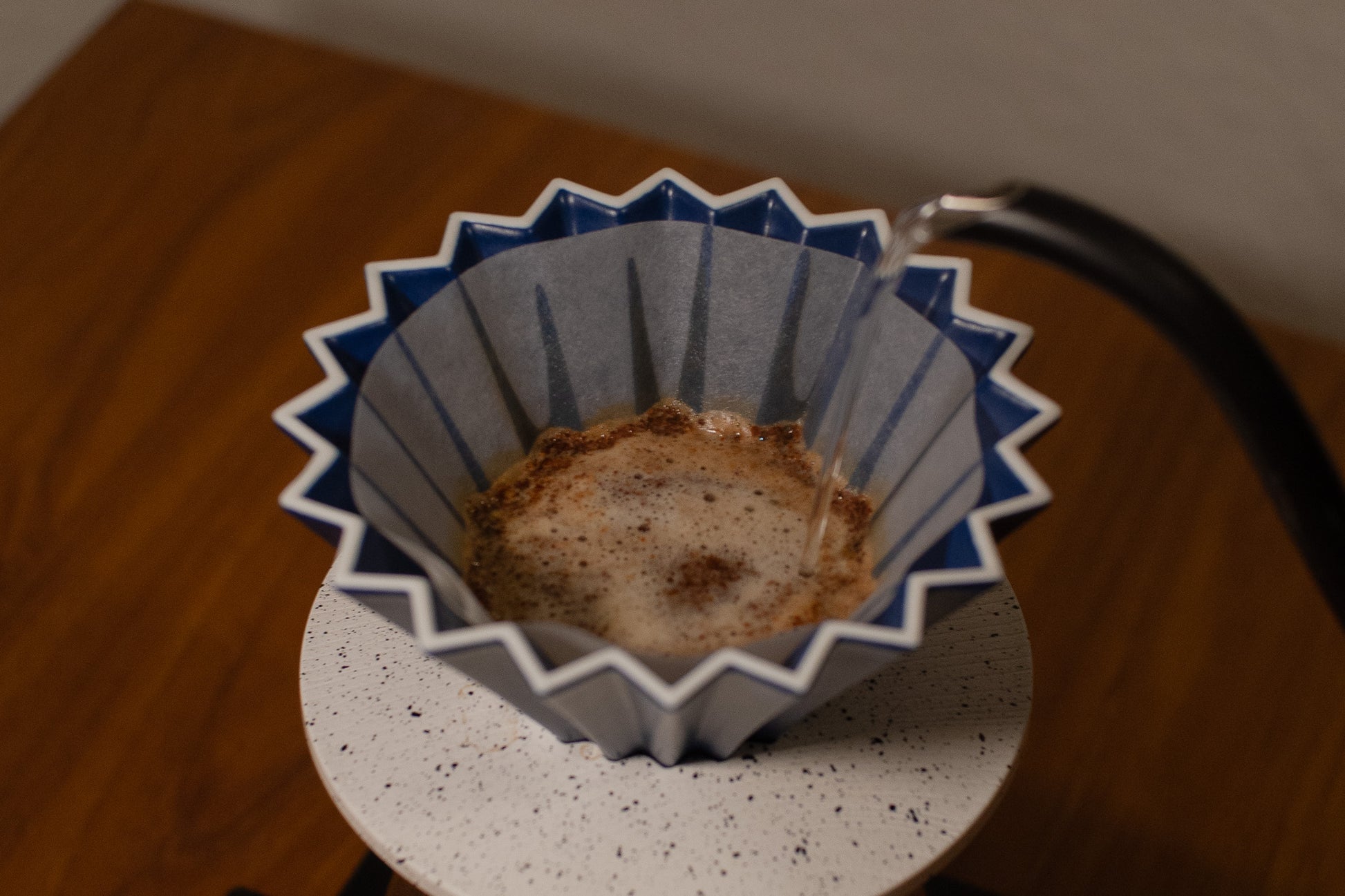Blue and white coffee filter with coffee grounds on a wooden surface