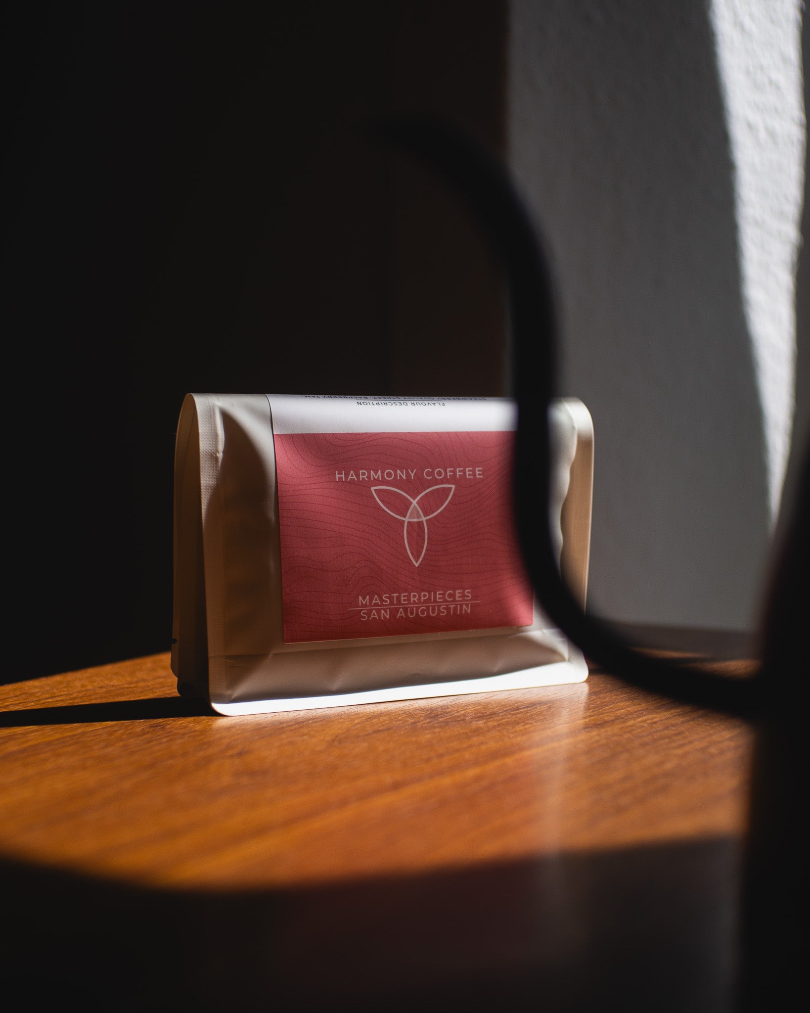 Harmony Coffee package on a wooden surface in direct sunlight.