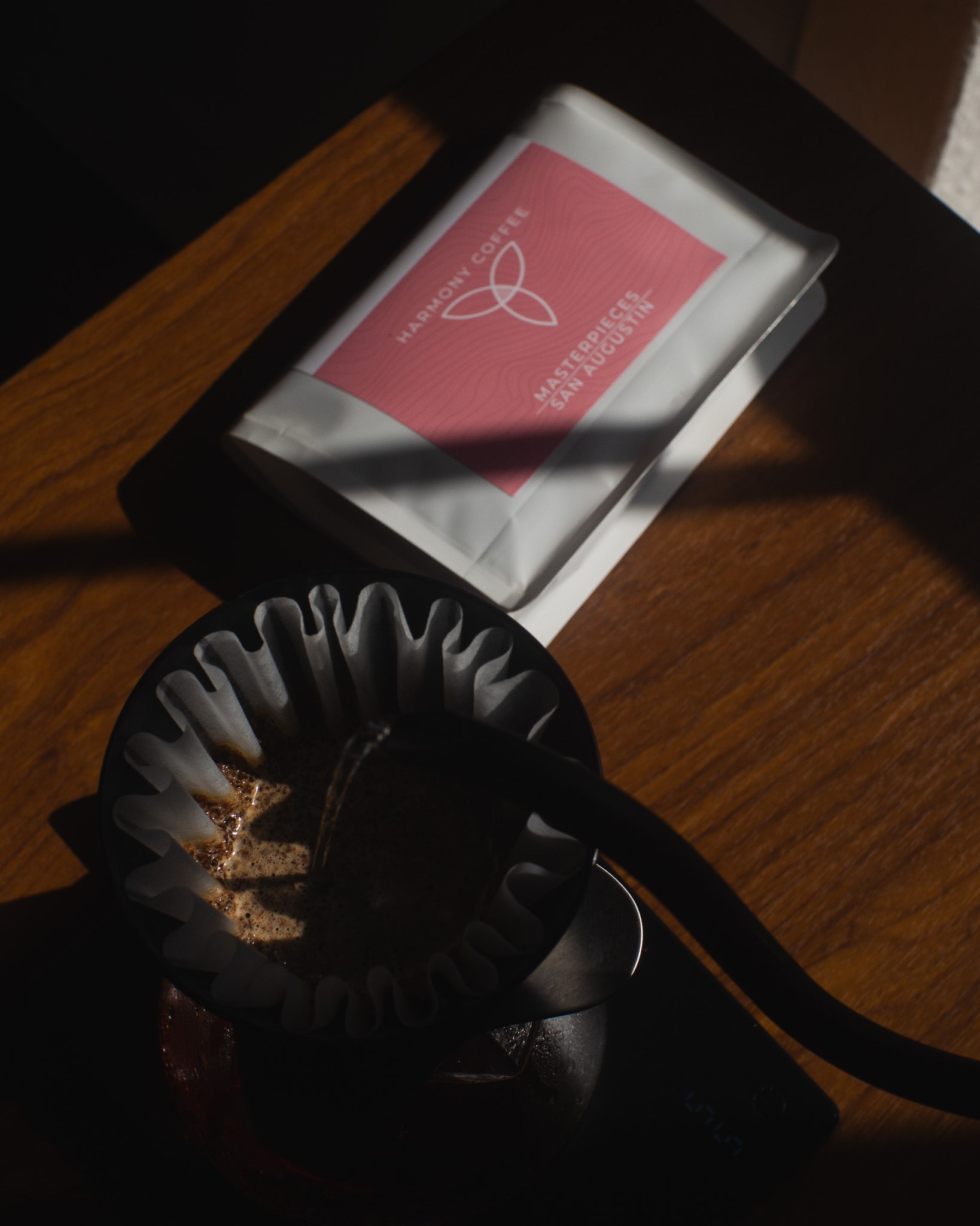 Coffee filter with ground coffee and a package of Sidra coffee from Ecuador on a wooden surface.