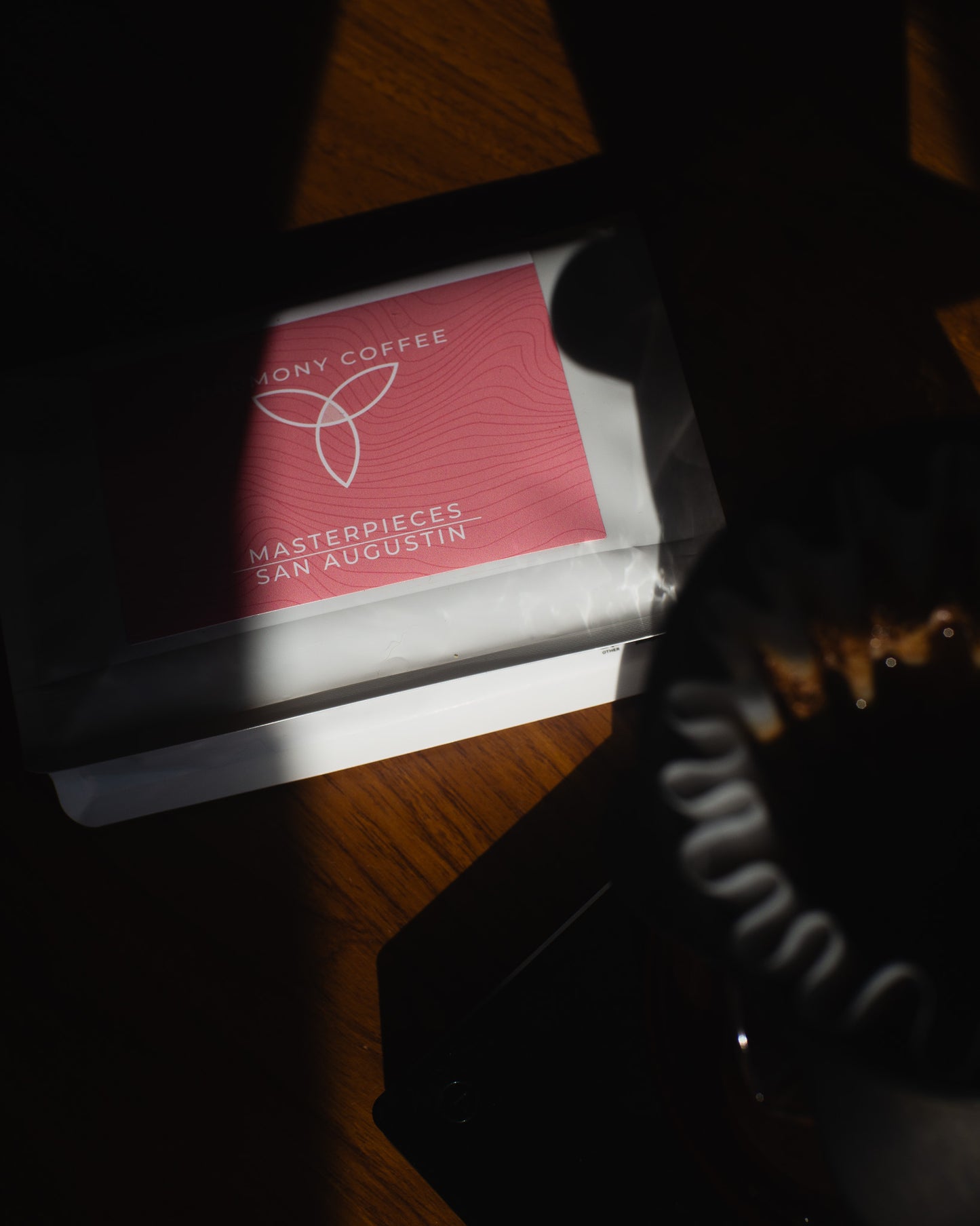 Red coffee bag with 'Harmony Coffee' branding on a wooden surface