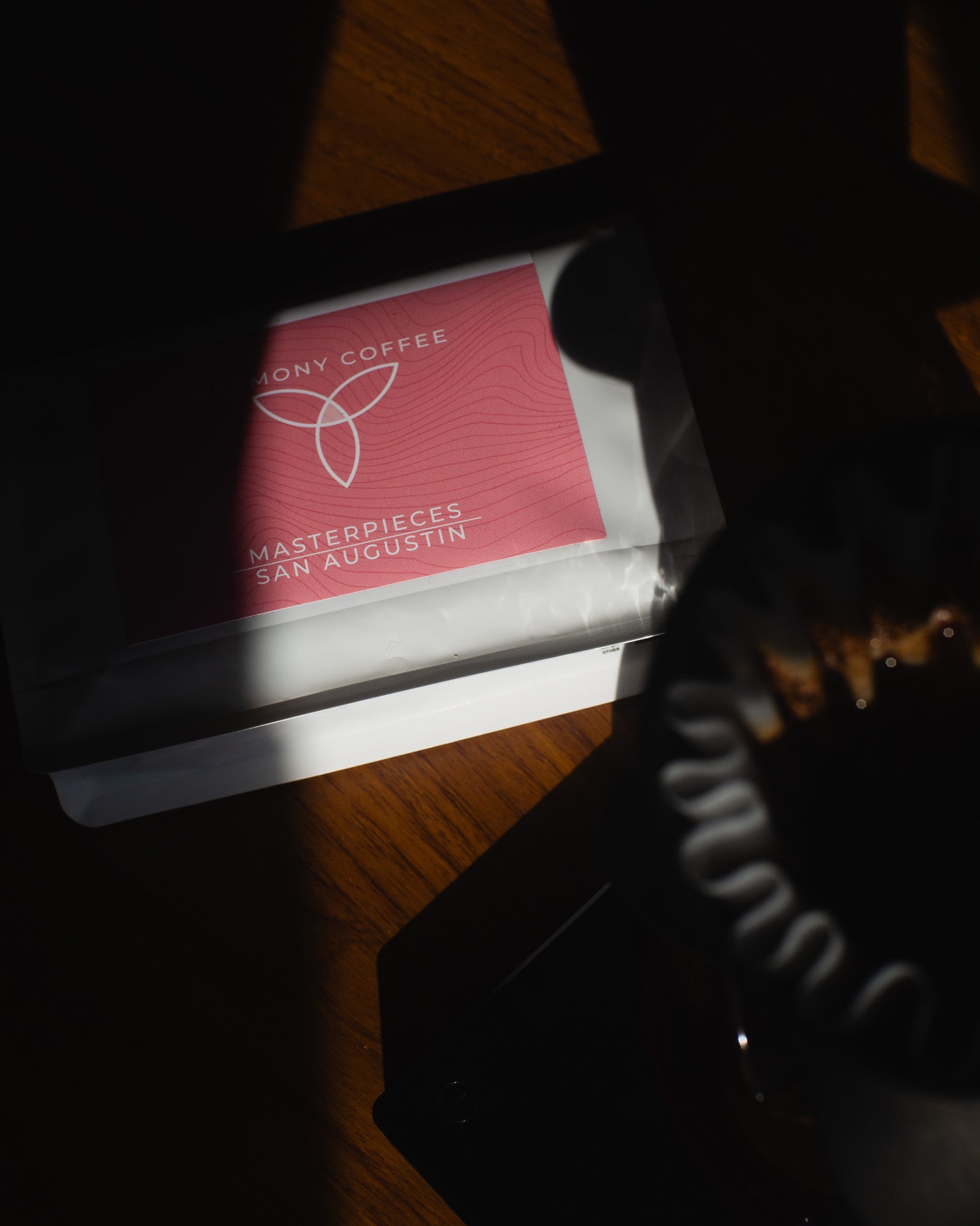 Red coffee bag with 'Harmony Coffee' branding on a wooden surface