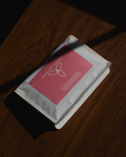 Harmony Coffee package of San Augustin Sidra from Ecuador on a wooden surface with a shadow passing across the bag.