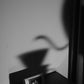 Shadow of a kettle pouring into a dripper cast on the wall above the Spooky & Scary YunLan Estate coffee bag