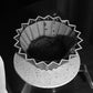 Water dripping into a blooming bed of YunLan Estate coffee in a white origami dripper