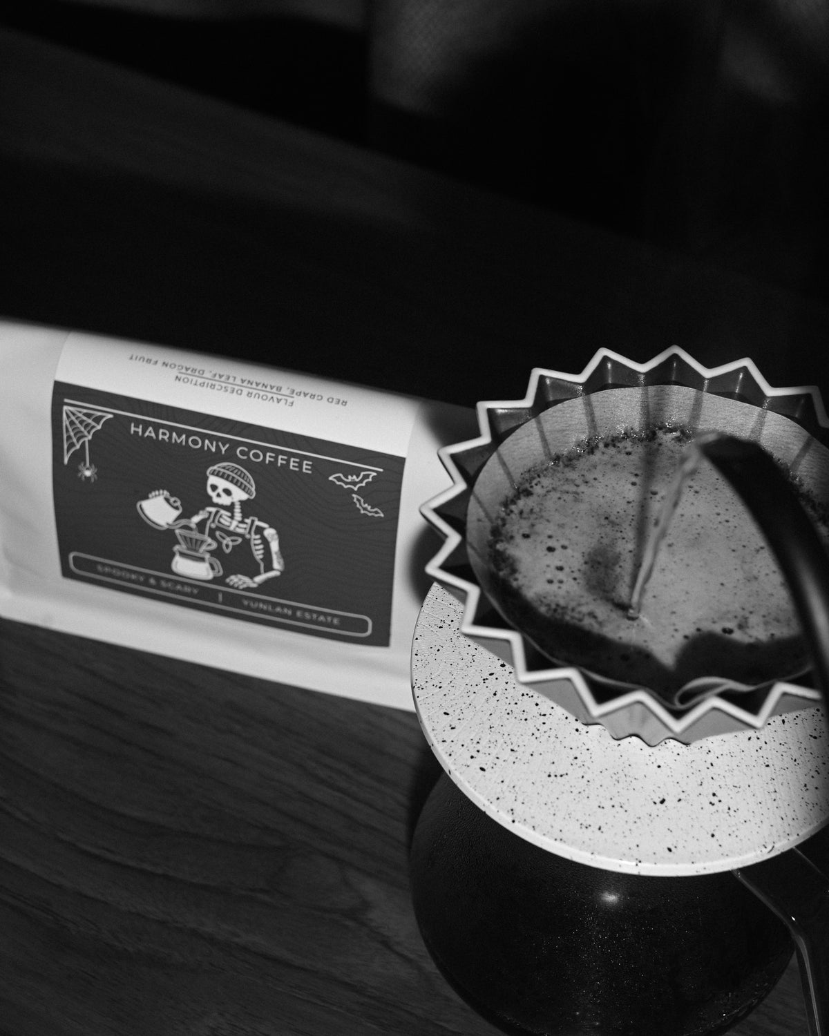 Water pouring into an origami dripper while brewing YunLan Estate, with the Spooky & Scary bag behind